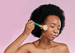 Black woman, brush and makeup with beauty and skin, foundation or powder application on pink background. Cosmetic tools, skincare and African model glow, cosmetology and facial, self care in studio