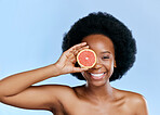 Black woman, smile in portrait with grapefruit and beauty, natural cosmetic treatment on blue background. Fruit, citrus and vitamin c, eco friendly skincare and happy female model with sustainability