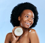 Beauty, skin and coconut with a model black woman in studio on a blue background for natural treatment. Thinking, skincare and cosmetics with a happy young female person holding fruit for oil