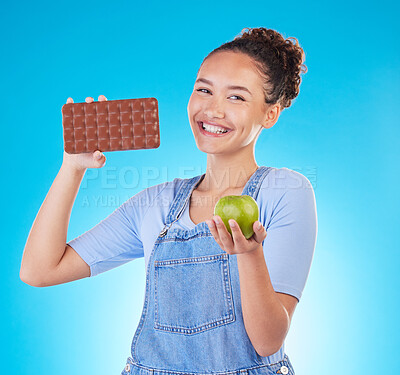 Buy stock photo Apple, chocolate and woman for healthy food choice or offer isolated on studio, blue background for food, sugar and diet. Dessert, green fruit and happy young person for detox or lose weight decision