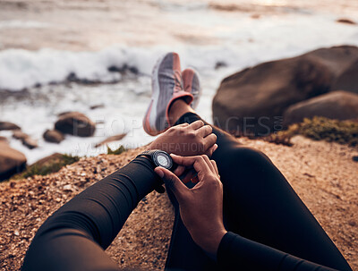 Buy stock photo Relax, check and smart watch with hand of woman on rock for running, fitness tracker and heart rate. Workout, exercise and goal with closeup of female runner at beach for monitor, goals and time