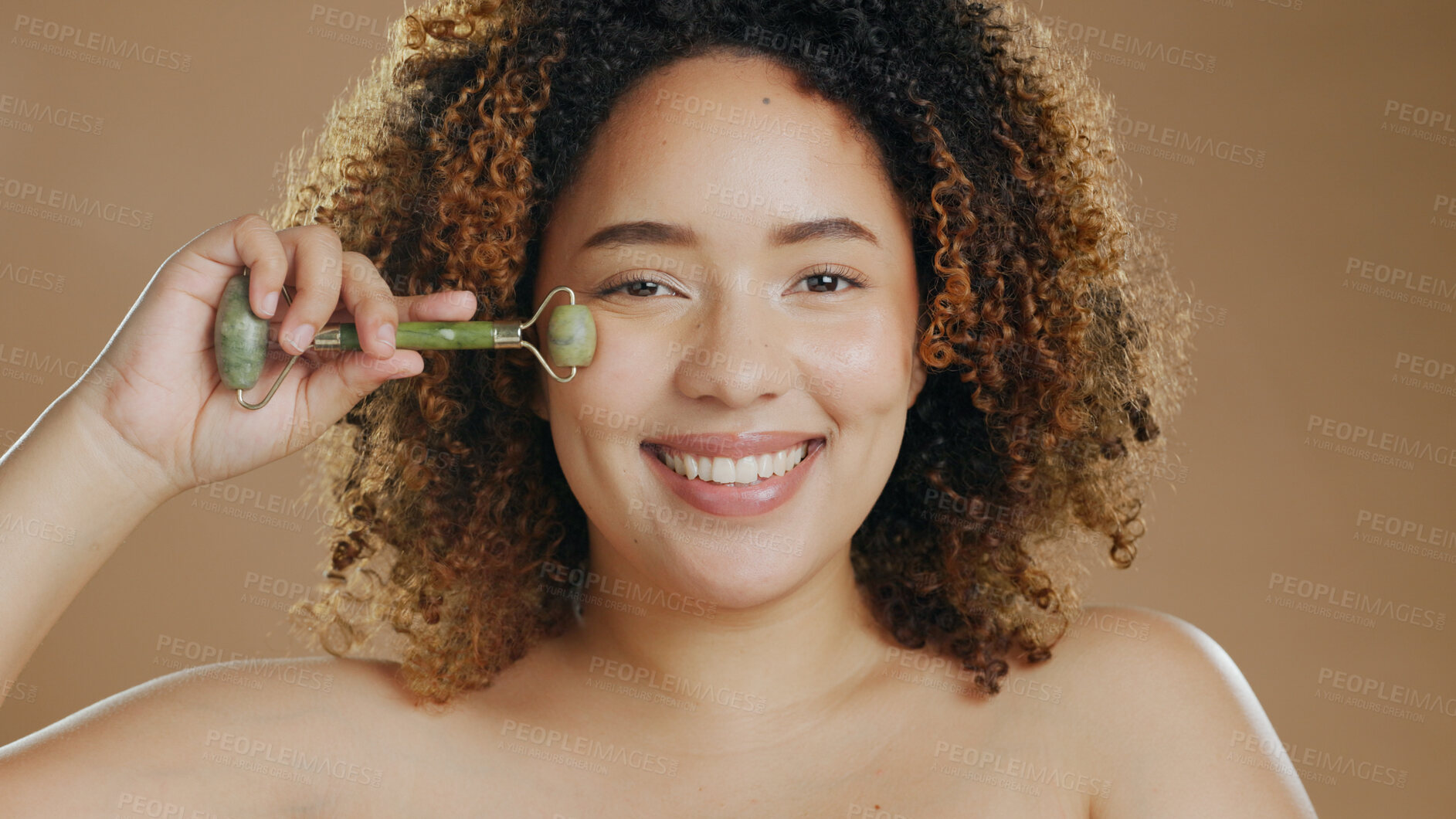 Buy stock photo Happy woman, portrait or jade roller in studio with anti aging product or facial tool on brown background. Smile, beauty or proud biracial girl model with cosmetics for wellness or natural skincare