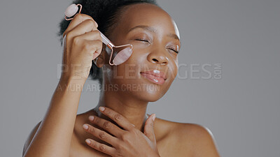 Buy stock photo Black woman, face with roller and massage for beauty and skincare, natural cosmetics and treatment on white background. Wellness, dermatology and skin glow, rose quartz crystal and tools in studio