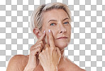 Portrait of one mature caucasian woman popping a zit during a skin care routine while posing against a grey copyspace background. Older model with a pimple targeting acne in a studio