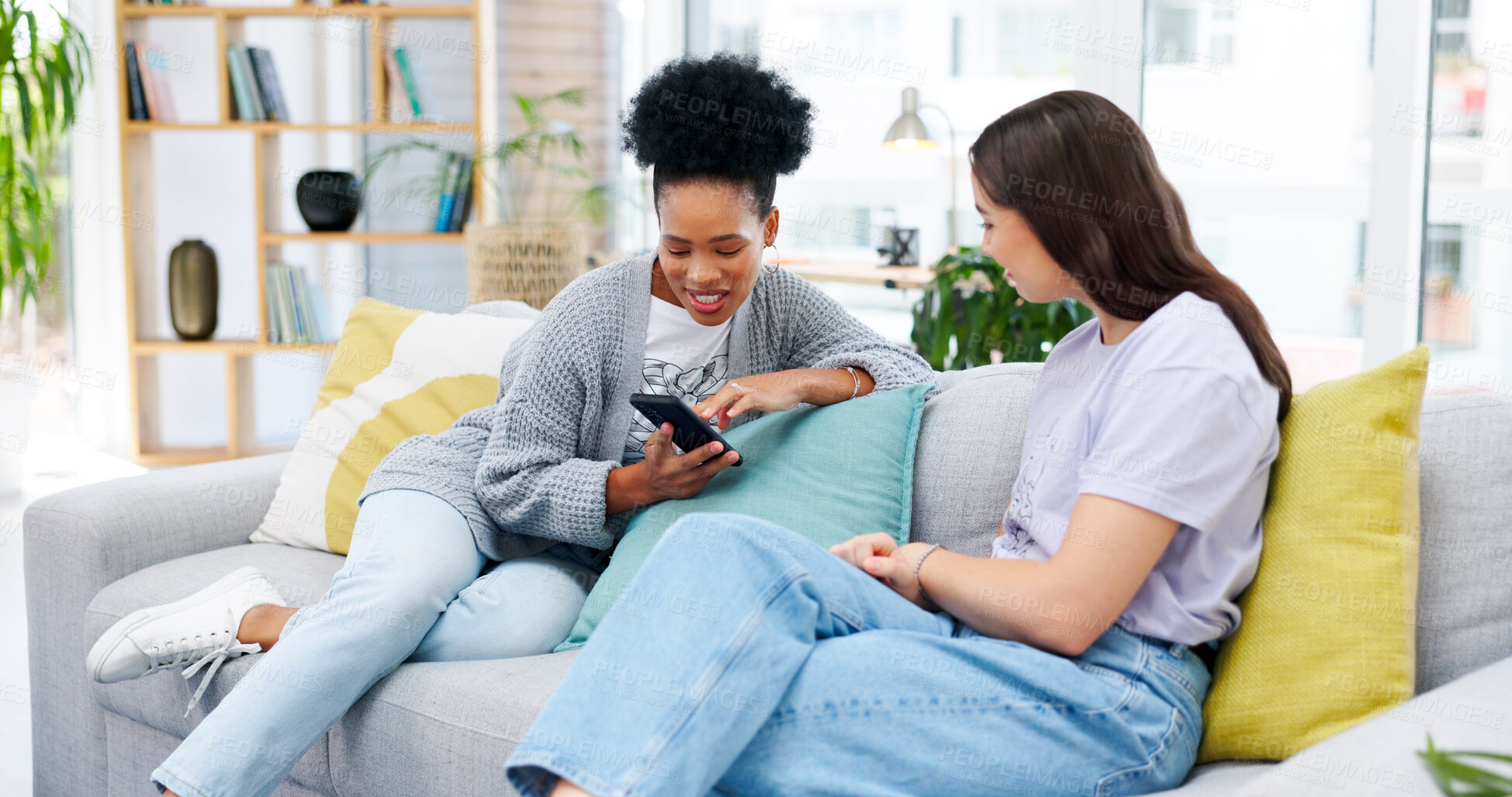 Buy stock photo Cellphone, conversation and girl friends on sofa talking, bonding and networking on social media or mobile app. Happy, discussion and young women scroll on a phone in living room of modern apartment.