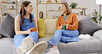 Coffee, relax and friends on a sofa talking, content and bonding on the weekend together. Tea, women and conversation on a couch, smile and chilling in a living room while enjoying comforting drink