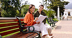 Women, friends and laughing at park on bench, bonding and talking together. Girls, outdoor and happiness of people in conversation, comic discussion or comedy and enjoying quality time for friendship