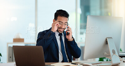 Buy stock photo Happy business man talking on his phone while working on a computer and smiling alone at work. Young corporate professional having a discussion and explaining project details to a colleague or client