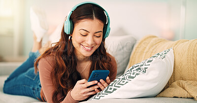 Buy stock photo Girl, phone and music on sofa to relax with headphones with smile, typing and happy on social media. Woman, smartphone and streaming song on internet while reading communication, blog post or email