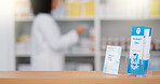 Focus on an information pamphlet on a counter at a pharmacy, advertising treatment and health care with a pharmacist packing rows medication on a shelf in a modern drugstore against blur background