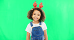 Children, christmas and a girl on a green screen background in studio wearing a reindeer antlers headband. Kids, portrait or festive with an adorable little female child feeling happy in the holidays