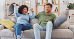 Pillow fight, happy couple and fun in living room for love, silly game and energy at home. Cushion, fighting and excited man being playful with young woman, partner and laughing together on couch