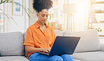 Laptop, thinking and woman typing on sofa in home living room, working or social media. Computer, remote worker and happy mixed race person or freelancer writing email, research or online browsing.