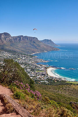 Buy stock photo Landscape, copy space and ocean view of mountain hiking trail with fynbos flowers. Paraglider flying over mountains, sea and city in extreme adrenaline sport or adventure hobby in travel destination