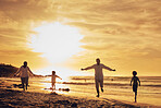 Family, freedom with silhouette on beach at sunset, parents and kids running together with travel, care free and happy outdoor. Man, woman and children, ocean waves and vacation, nature and happiness
