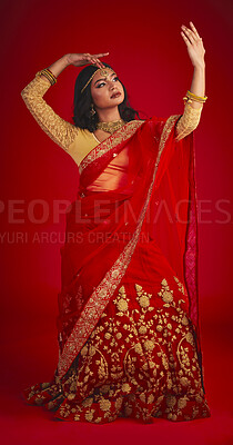 Buy stock photo Beauty. dance and Indian woman in a traditional dress, jewellery and religion against a red studio background. Female person, girl and dancer with a cultural outfit, dancing and routine with fashion