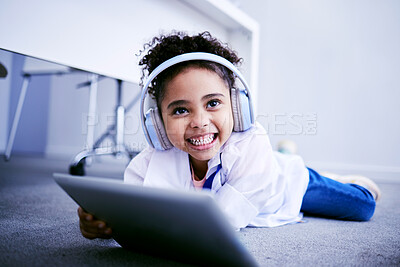 Buy stock photo Tablet, headphones and education with a student girl lying on the floor on her home for distance learning. Technology, virtual class and smile with a happy young female pupil watching a school video