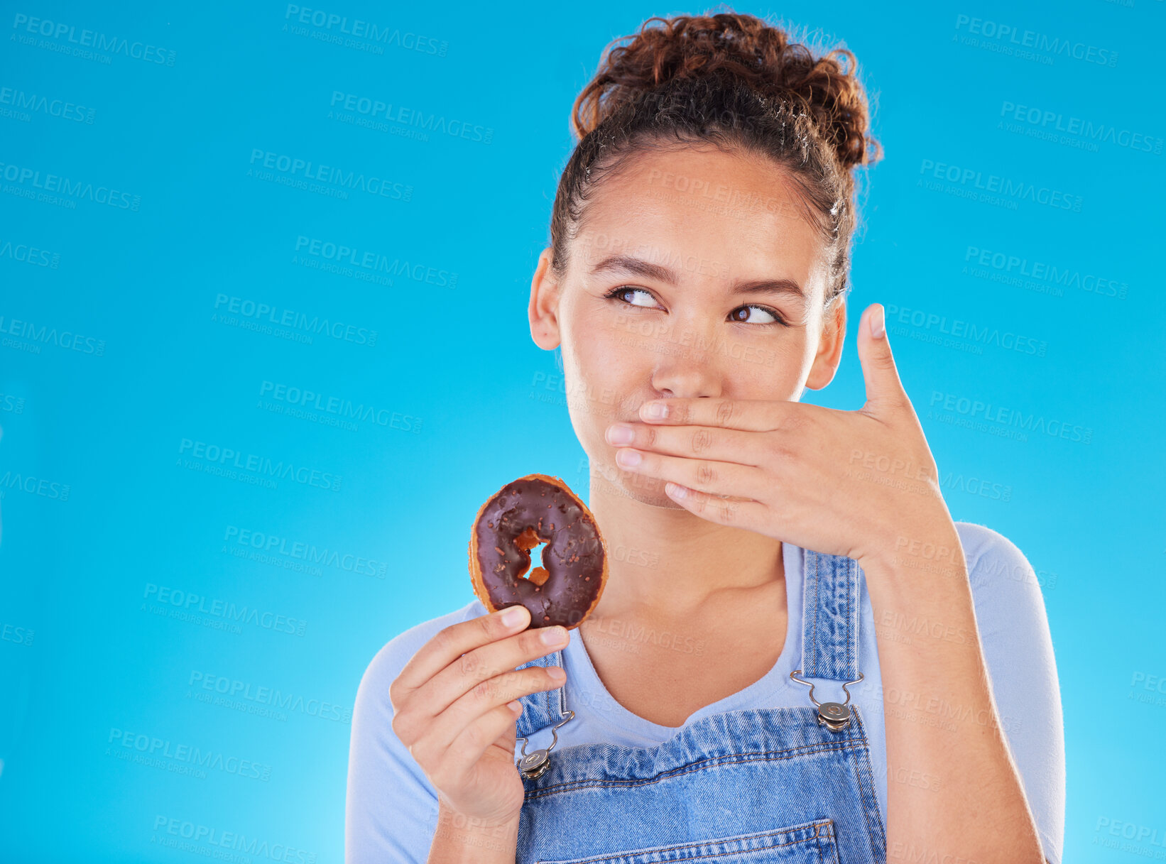 Buy stock photo Chocolate, diet and donut with woman in studio for fast food, dessert and nutrition. Happy, cake and sugar with person eating on blue background for candy, health and hungry with mockup space