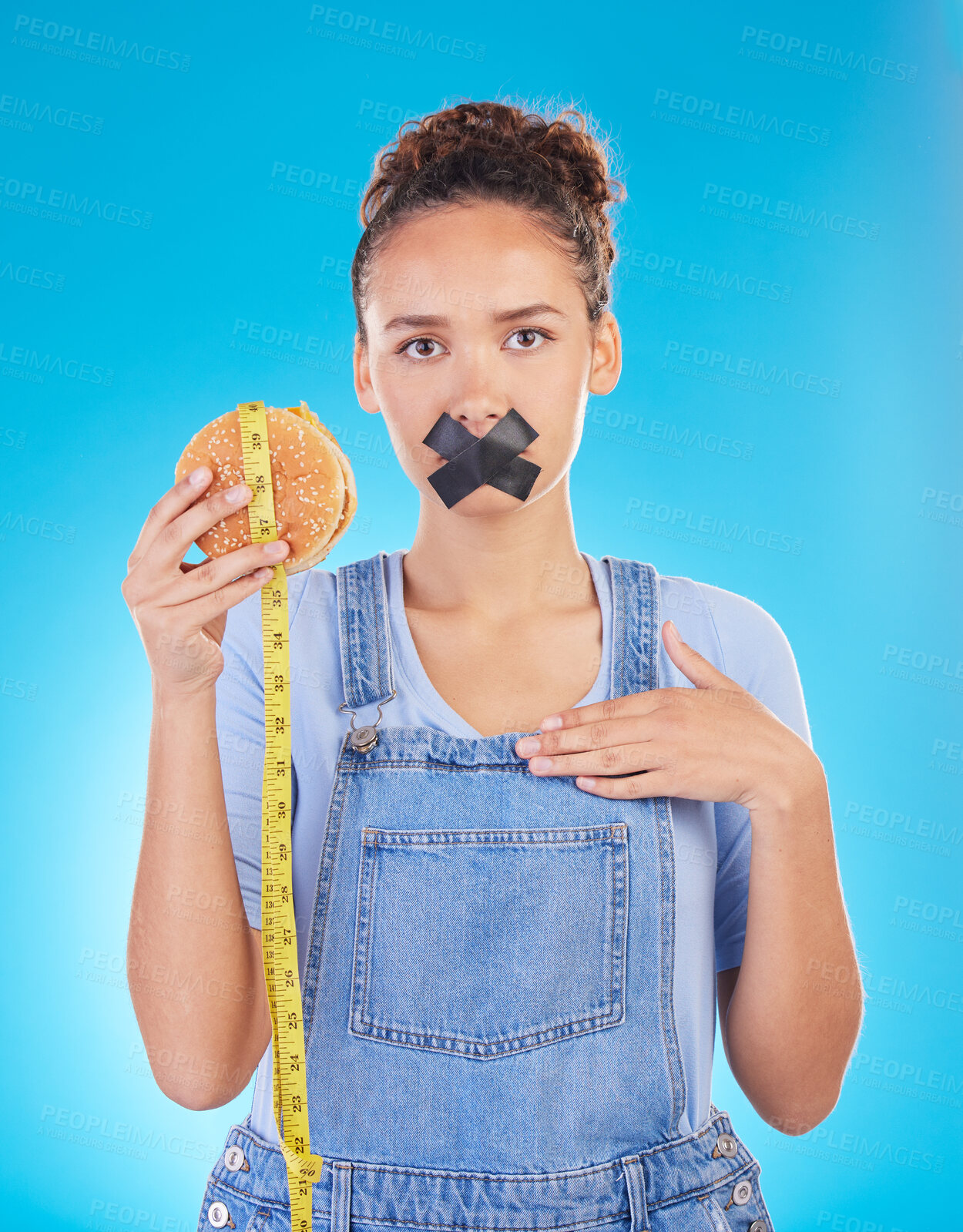 Buy stock photo Burger, diet and woman tape mouth for fast food and weight loss gives bad, disgust and frustrated review for protection. Disaster, mistake and person disappointed isolated in a studio blue background