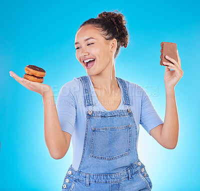 Buy stock photo Food, diet and happy woman with sweets in studio, chocolate and donut for eating plan on blue background. Health, nutrition and choice to lose weight, girl with smile and freedom for sugar or dessert