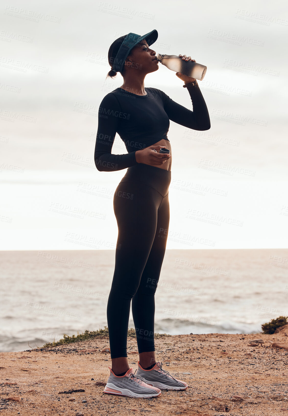 Buy stock photo Drinking water, fitness and woman on mountain for training, exercise or workout nutrition, health and wellness in nature. Liquid bottle, hiking and cardio of tired runner or person by ocean in sunset