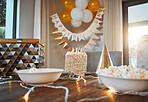 Birthday, party and cake on table with decoration in living room for event, celebration and social gathering. Food, surprise and closeup of dessert, snacks and sweet treats with presents at home