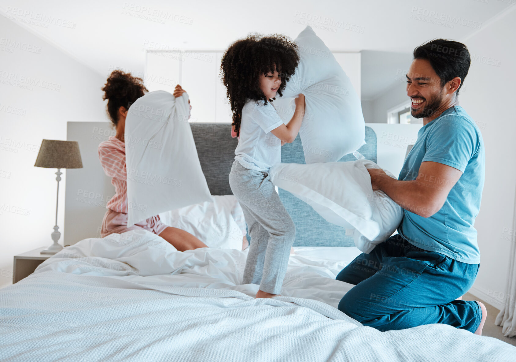 Buy stock photo Happy family, pillow fight and playing on bed in the morning together for fun bonding at home. Father, mother and playful children enjoying game, entertainment or fighting with pillows in the bedroom