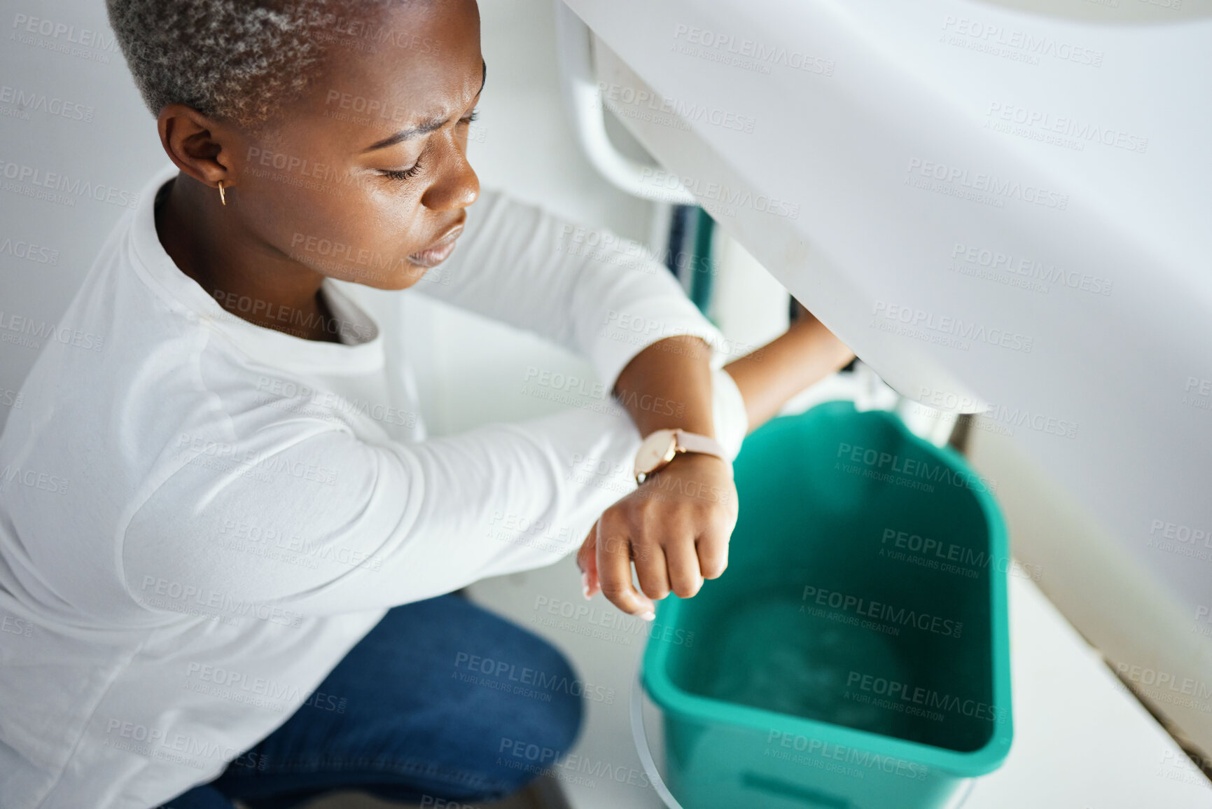 Buy stock photo Plumbing, leak and watch with a black woman in the bathroom of her home waiting for repair assistance. Sink, emergency and time with a young female homeowner in her house to stop water using a bucket