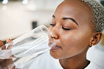 Wellness, glass and woman drinking water for health, hydration and liquid nutrition at her home. Thirsty, energy and African female person enjoying cold healthy drink in the kitchen of her apartment.