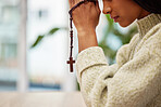 Hands, rosary and woman praying for help, faith or gratitude to God, praise and humble in her home. Jesus, worship and lady person in prayer with religious cross for hope, trust or Christian guidance