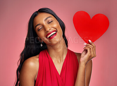 Buy stock photo Funny, heart and valentines day with a woman on a pink background in studio for love or romance. Smile, emoji and social media with a young female comic holding a shape or symbol of affection