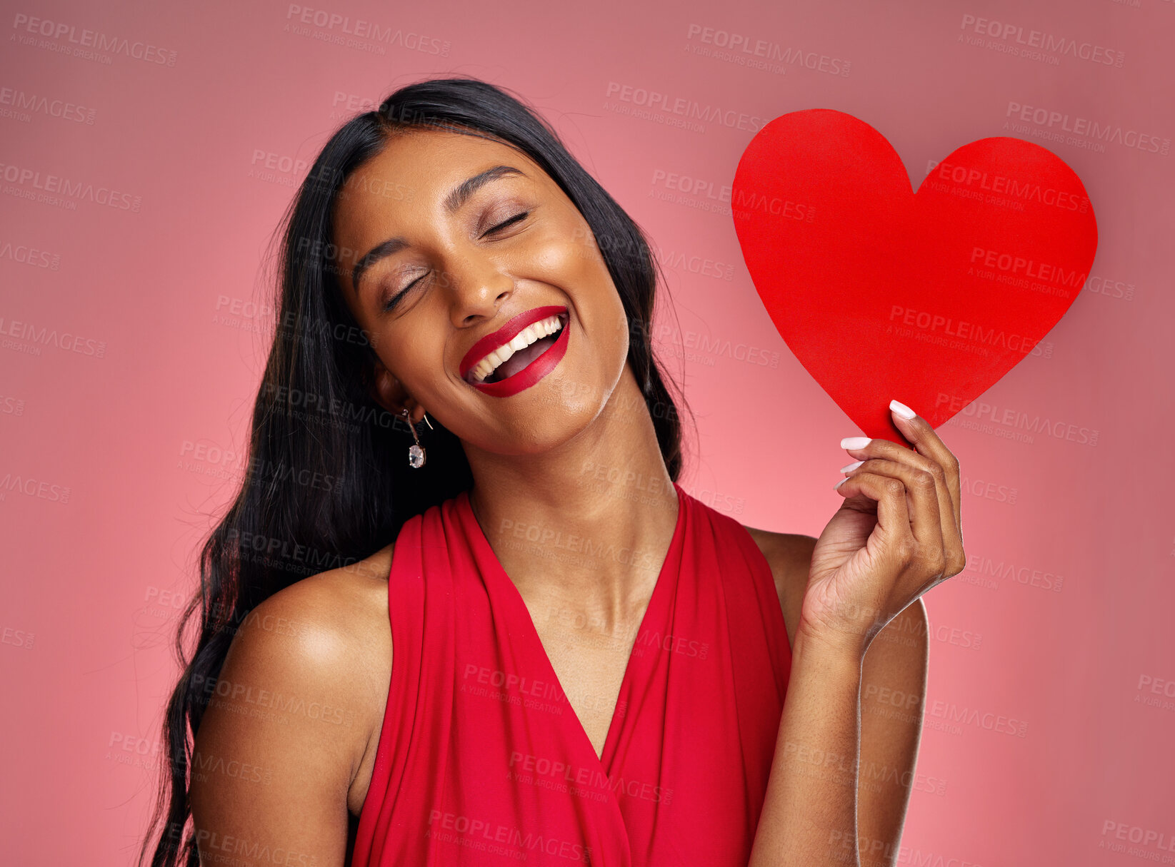 Buy stock photo Funny, heart and valentines day with a woman on a pink background in studio for love or romance. Smile, emoji and social media with a young female comic holding a shape or symbol of affection