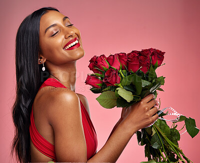 Happy, beauty and face of a woman with a roses on a studio background for valentines day. Makeup, model and young Indian girl with a flower bouquet and laugh for romance or love on a pink backdrop