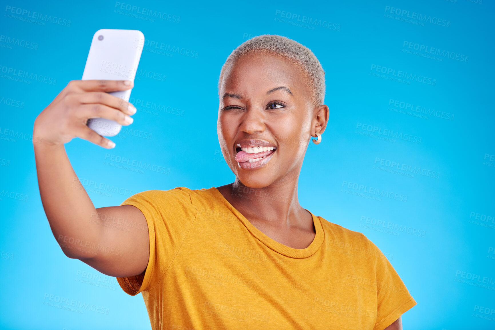 Buy stock photo Social media, selfie and funny face with a black woman on blue background in studio to update her profile picture. Post, app and a happy young female influencer taking a photograph for her status