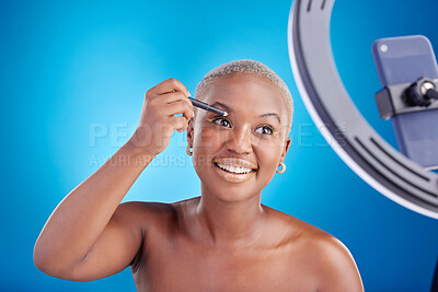 Buy stock photo Black woman, makeup and face of blogger with eyeliner in studio for beauty, skin glow and shine cosmetics. African female influencer with video tutorial, self care and facial on a blue background 