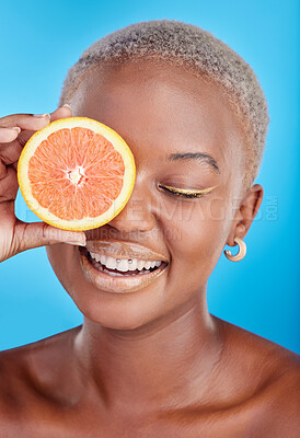 Buy stock photo Orange fruits, skincare and face of black woman in studio, blue background and eco makeup cosmetics. Beauty, happy female model and citrus for vitamin c, facial detox or healthy aesthetic dermatology