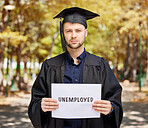 Portrait, graduation and unemployment with a student man holding a sign outdoor on university campus. Education, future and scholarship with an unhappy male college pupil showing the word unemployed