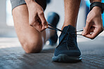 Fitness, shoes and laces with a sports man in the gym getting ready for a cardio or endurance workout. Exercise, running and preparation with a male athlete or runner in a training center closeup