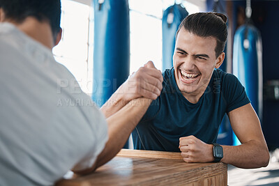 Buy stock photo Strong, active and men arm wrestling in the gym on a table while being playful for a challenge. Rivalry, game and male people or athletes doing strength muscle battle for fun, bonding and friendship.