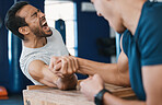 Strong, loser or men arm wrestling at gym on a table in playful challenge together in fitness training. Game, pain or strong people in muscle power battle for sports, hard competition or tough match