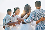Happy friends, back and hug on beach for sunset holiday, vacation or weekend together in nature. Rear view group of people standing for quality bonding time, trip or travel by the ocean coast outside