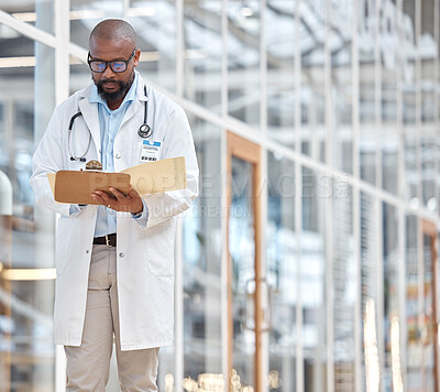 Buy stock photo Black man, doctor and reading notes on clipboard with research documents, healthcare schedule or test results in hospital. Male medical worker, walking and planning report of insurance info in clinic