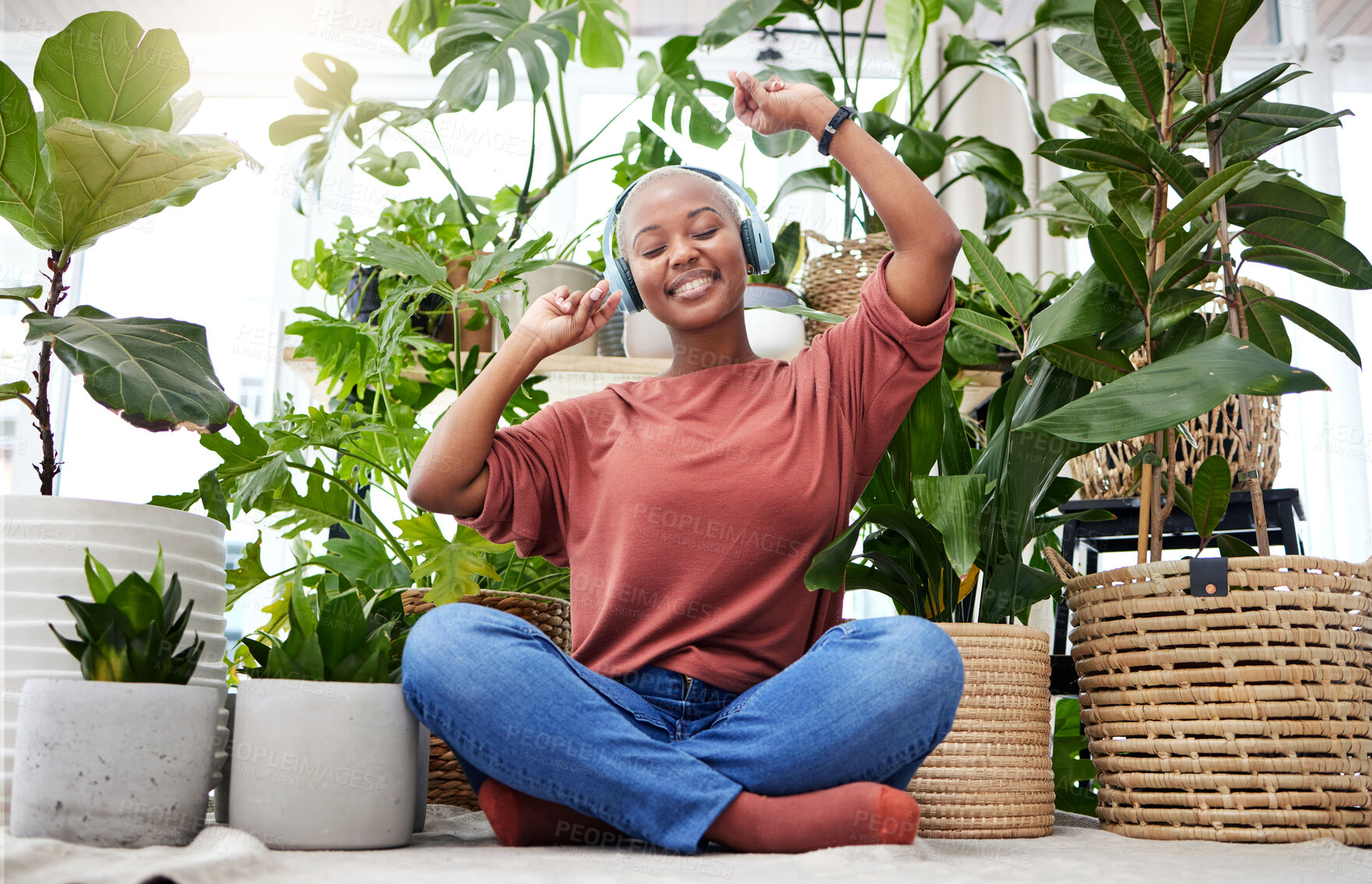 Buy stock photo Music, dance or freedom with a black woman in her home by plants while listening to an audio playlist. Headphones, flare and subscription service with a carefree young person streaming in a house