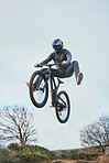 Mountain, bike jump and person doing jump on a bicycle for extreme sports competition stunt or training in nature. Skill, contest and athlete workout or practice sky or air trick for fitness