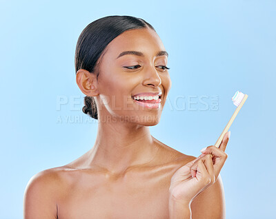 Buy stock photo Face, toothbrush and a woman brushing teeth for dental health on a blue background for wellness. Happy indian female model with toothpaste and brush for a clean, fresh and healthy mouth in studio