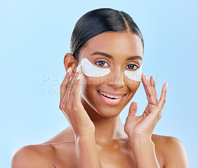 Buy stock photo Happy, skincare and portrait of woman with patches for eyes, dark circles and treatment. Smile, face and Indian girl or model with a facial collagen for a glow isolated on a blue background in studio
