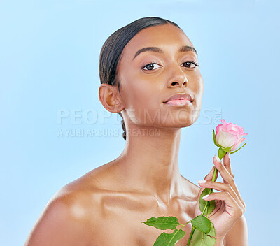 Buy stock photo Woman, skincare and rose with natural beauty, portrait and eco friendly dermatology on blue background. Female model, face and shine, healthy skin glow and flower, nature and cosmetics in studio