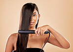 Beauty, flat iron and hair care of a woman in studio with natural glow and shine. Straightener, cosmetics and wellness of Indian person for hairdresser, hot tools or salon results on beige background
