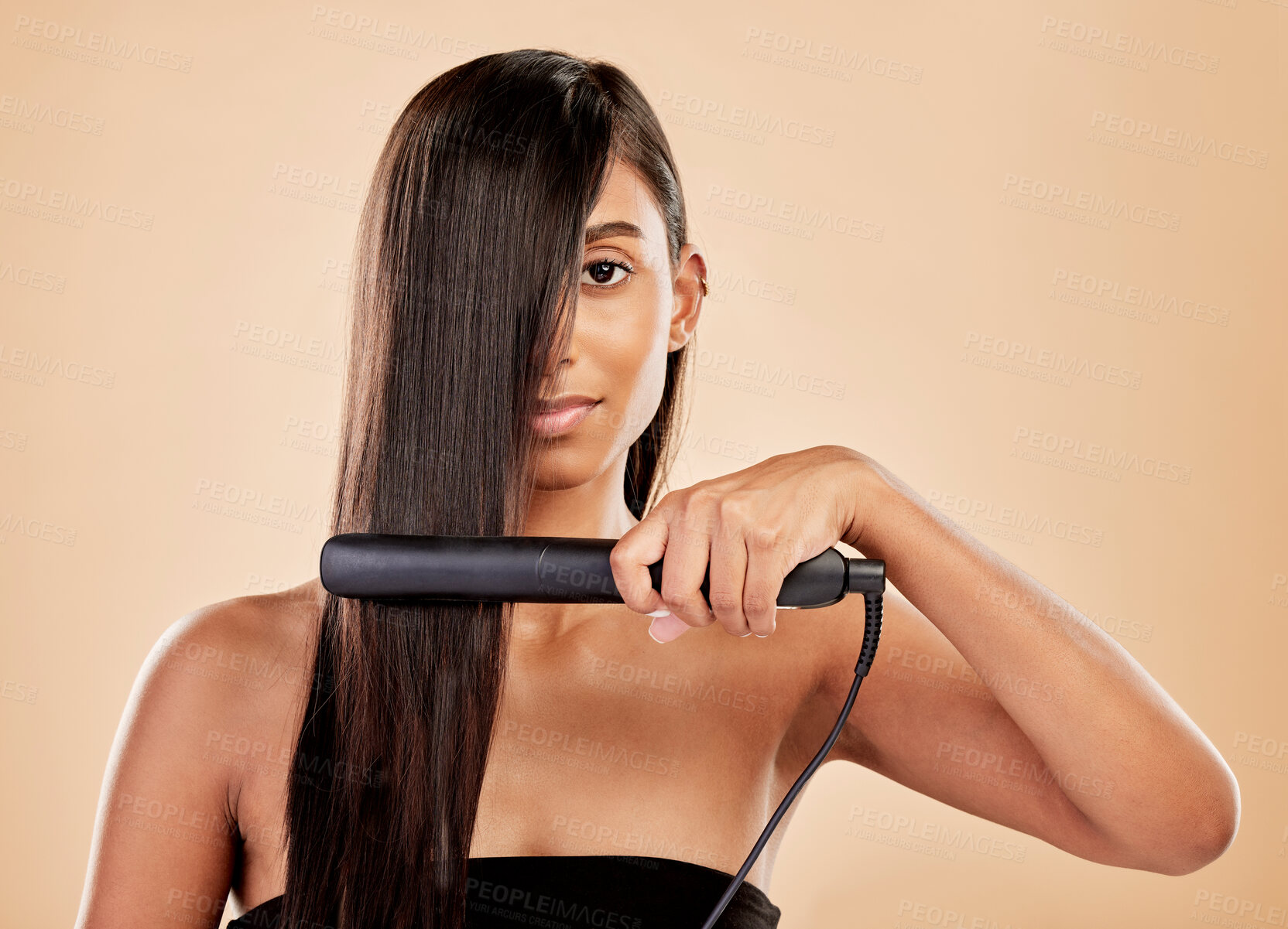Buy stock photo Beauty, flat iron and hair care of a woman in studio with natural glow and shine. Straightener, cosmetics and wellness of Indian person for hairdresser, hot tools or salon results on beige background
