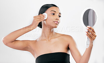 Buy stock photo Woman, mirror and cotton pad for face, cosmetics and aesthetic skincare in studio on white background. Indian female model looking at reflection with beauty product for facial cleaning or dermatology